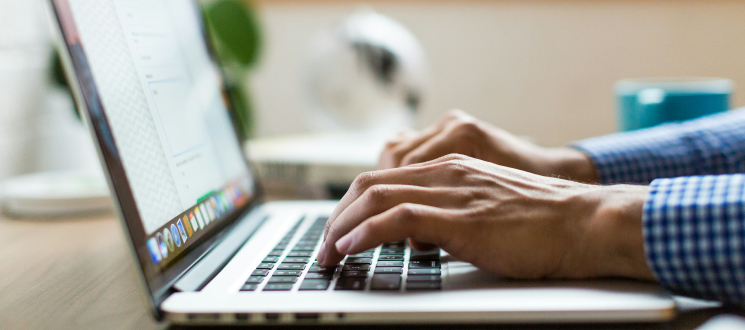 Manos escribiendo en un portátil.