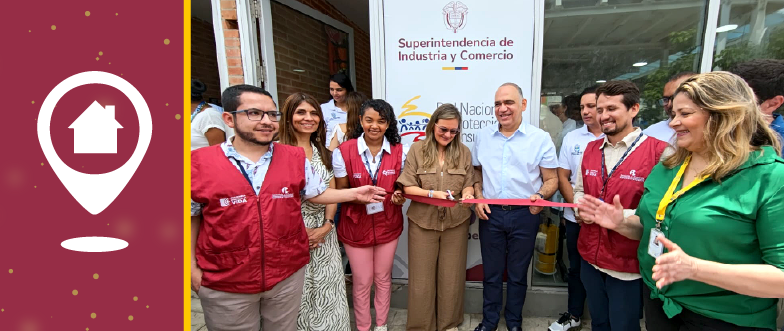 Un grupo de personas sonrientes cortando una cinta roja frente a un cartel de la "Superintendencia de Industria y Comercio". A la izquierda, un ícono de ubicación con una casa.