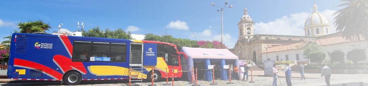 Imagen contiene Foto del bus oficina y carpa inflable de la RNPC, estacionados en una plaza pública.