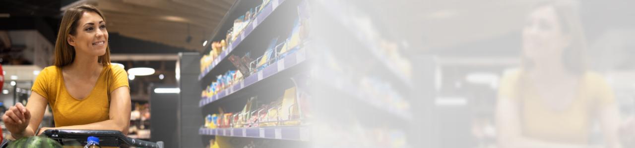 Image contains a photograph of a woman standing with a shopping cart alongside a product stand inside a supermarket