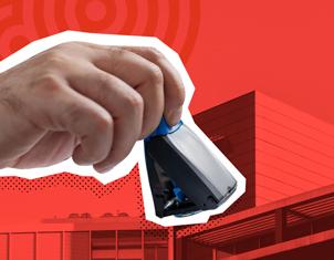 Primer plano de una mano sosteniendo un sello de goma automático, lista para estampar un documento. El fondo es de color rojo intenso y muestra la silueta de un edificio institucional.