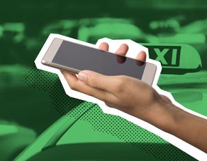 Primer plano de una mano sosteniendo un smartphone con la pantalla apagada. El fondo verde oscuro muestra el techo y la luz de un taxi con la palabra "TAXI" visible.