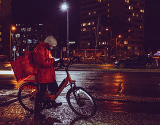 se muestra un domiciliario de rappi con su celular en una bicicleta 