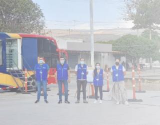 Imagen contiene fotografía de 5 personas ubicadas de pie en un espacio abierto y delante de un bus oficina.