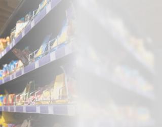 Image contains a photograph of a woman standing with a shopping cart alongside a product stand inside a supermarket