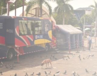 Imagen contiene fotografía del bus oficina y carpa de la RNPC situados en una plaza pública.