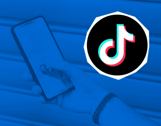 Una mano sosteniendo un celular con la aplicación de TikTok abierta, sobre un fondo azul con el logo de la red social resaltado a la derecha.