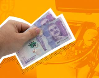 Una mano sosteniendo billetes de 50.000 pesos colombianos frente a un fondo naranja que muestra una terminal de pago.