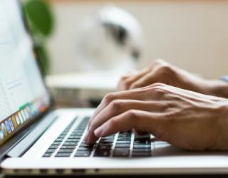 Manos escribiendo en un portátil.