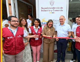 Un grupo de personas sonrientes cortando una cinta roja frente a un cartel de la "Superintendencia de Industria y Comercio". A la izquierda, un ícono de ubicación con una casa.